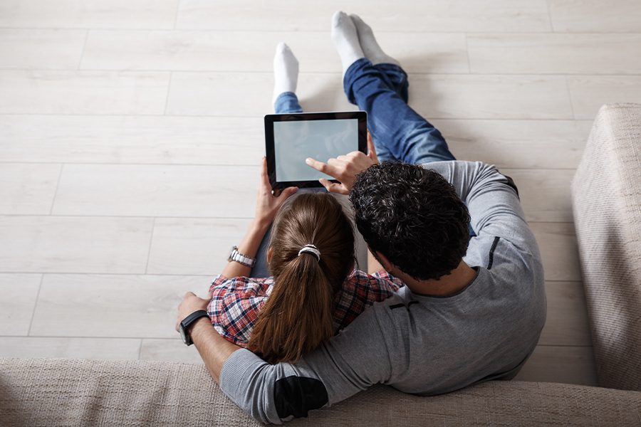 Blog - View Looking Down on a Couple Using Tablet Sitting on the Floor of Their Living Room