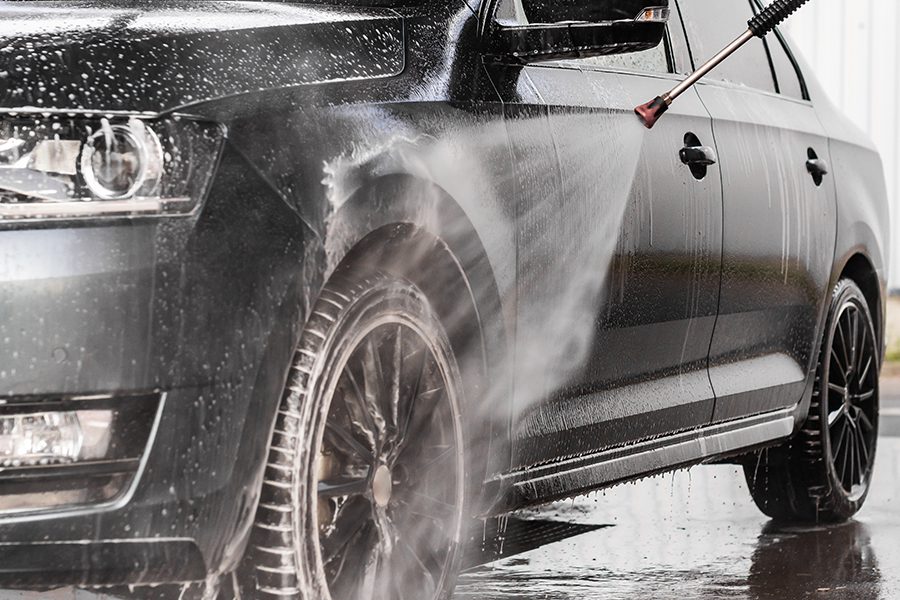 Car Wash Insurance - Closeup of a Black Sedan Car Being Power Washed