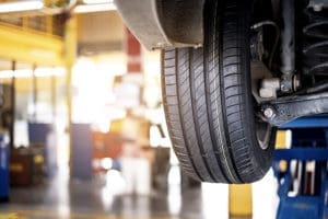Specialized Business Insurance - Closeup of Garage with Car Elevated and Background of Equipment and Machinery